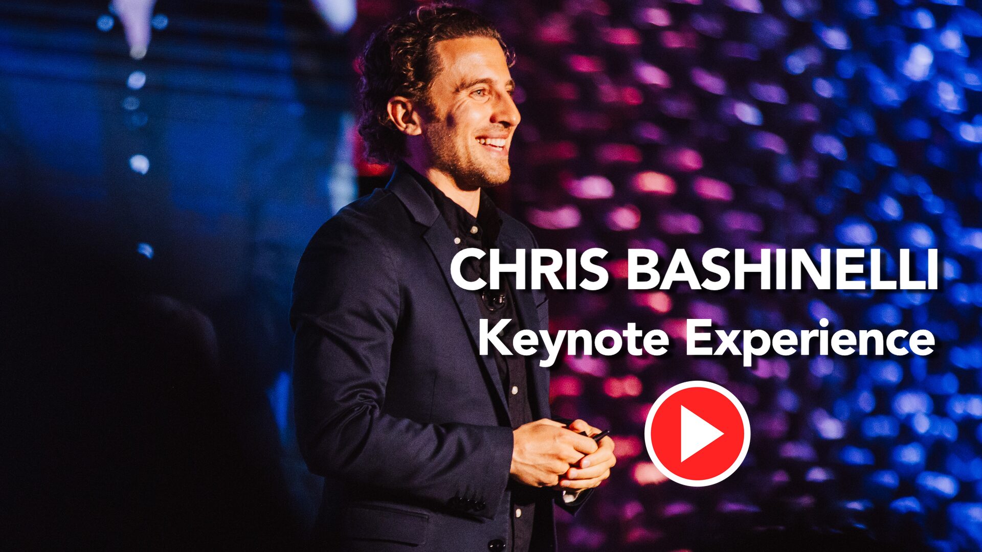 Portrait of Chris Bashinelli on stage during a keynote, with bold event text and a red play button graphic in the foreground.