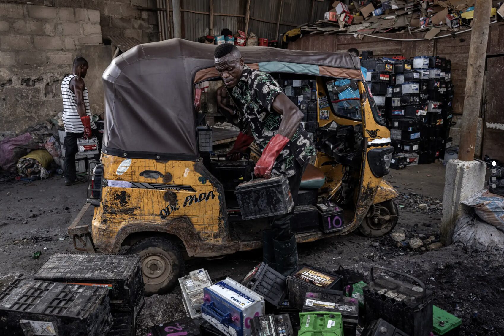 A procession of vehicles arrives at a muddy yard in Lagos. These are the pickers, who salvage and sell dead batteries. Finbarr O'Reilly for The New York Times