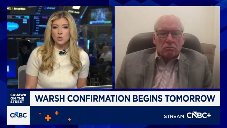 CNBC split-screen interview: female anchor on the left and an older man in a blazer on the right; banner reads 'WARSH CONFIRMATION BEGINS TOMORROW'.