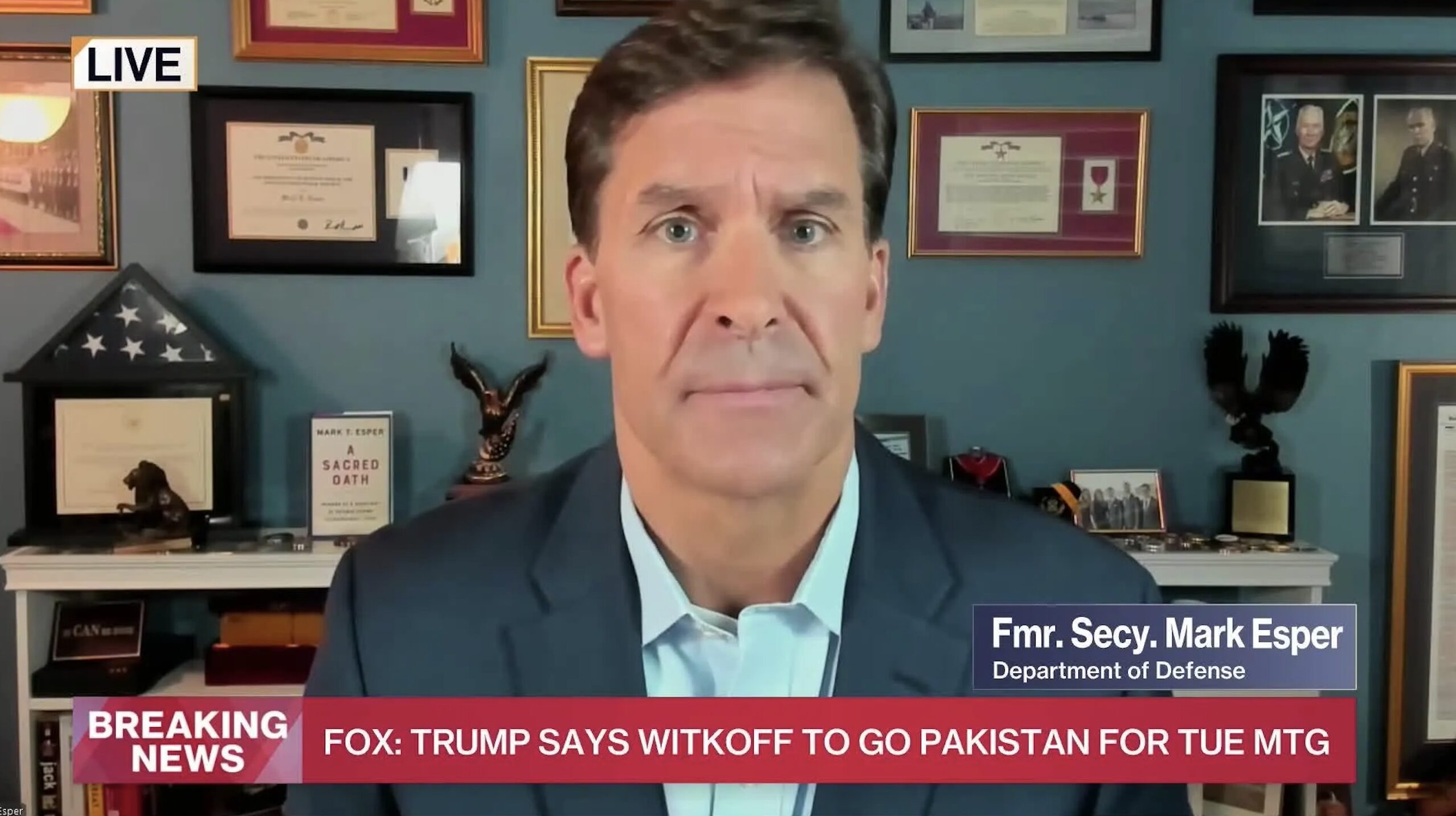 Live news screenshot of former Defense Secretary Mark Esper speaking; office wall with awards and framed photos in the background, 'LIVE' label visible.