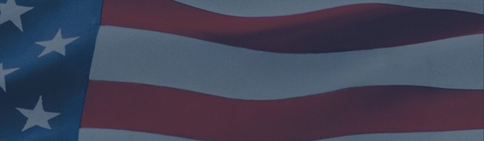 Partial view of a waving United States flag with white stars on a blue canton to the left and red-and-white stripes extending right.