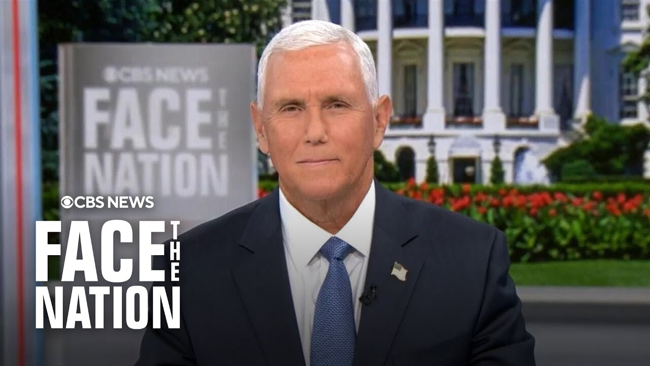 CBS News Face the Nation anchor seated at a news desk with the show's logo on screen and a formal outdoor backdrop behind him.